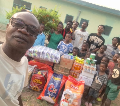 A staff member with children after a fresh delivery of food supplies